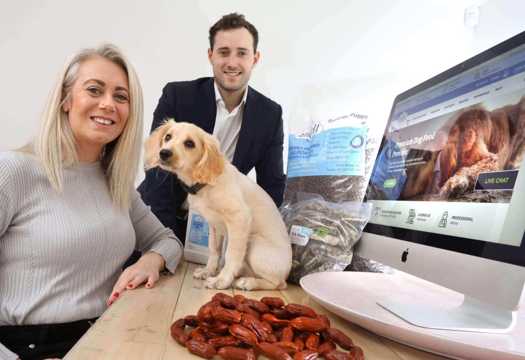 Two people and a dog looking at a computer screen