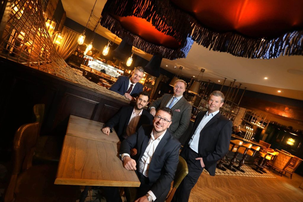 Five people posing for a picture at a bar