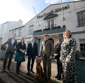 Six people and a dog standing outside of the Croft Hotel